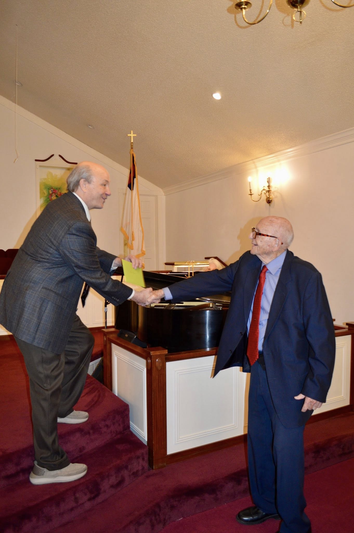 Two church members shaking hands at the front of the sanctuary